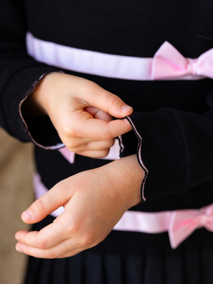 Black knit dress with pink satin bows and and pink trim contrast