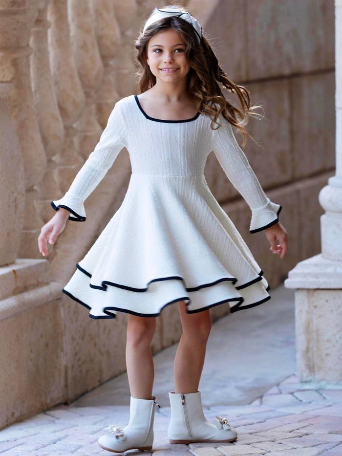 Elegant girls ivory twirl dress with ruffle sleeves and contrast trim.