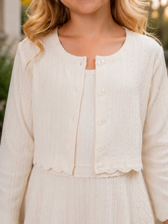Girls ivory dress and cardigan set with scalloped trim.