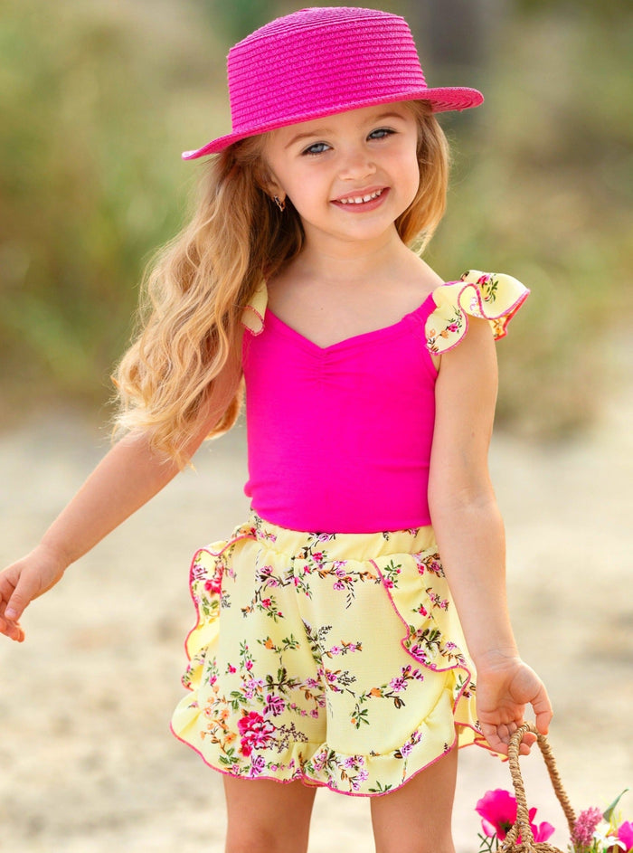 Girl wearing a pink sleeveless top with a yellow floral ruffle short from the spring collection by Mia Belle Girls
